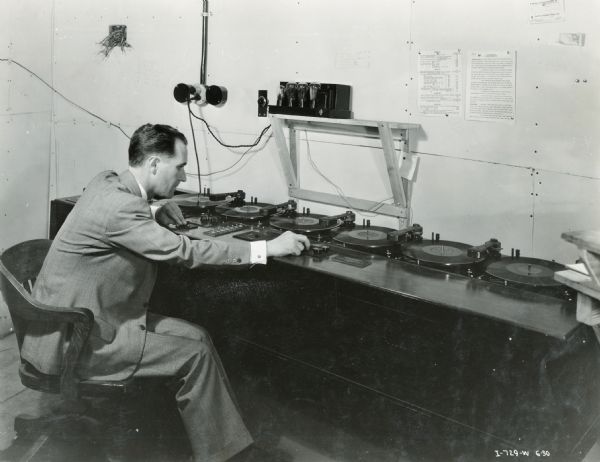 A man operating a series of phonograph turntables at the "A Century of Progress" world's fair. The turntables were likely connected to International Harvester's exhibit at the fair.
