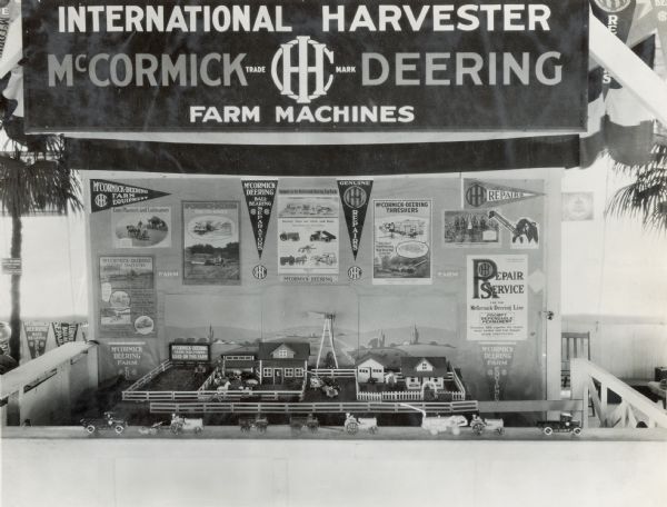 A miniaturized model of a farm set against a backdrop of advertising posters for International Harvester equipment. The model was on display at the Iowa State Fair.