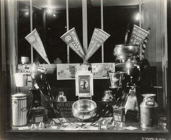 Various pieces of agricultural equipment sit on display in the window of The Winchester Store along with advertisements for the Primrose ball-bearing cream separator. The store may have been an International Harvester dealership. One of the Primrose advertisements reads: "Makes Child's Play of a Man's Job."