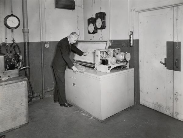 W.F. Borgerd, refrigeration engineer of International Harvester Company, looks at a milk cooler. The original caption reads: "W.F. Borgerd, refrigeration engineer of International Harvester Company, is examining a milk cooler in the refrigeration test department at Gas Power Engineering in Chicago.  Mr. Borgerd directed the experimental and developmental work which produced the Tomac Blood Plasma Bank, manufactured by the company."