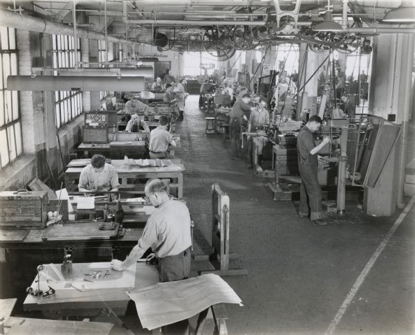 Elevated view of men working at stations in the machine shop of International Harvester Company's engineering department. The original caption reads: "Scene from a part of the machine shop of International Harvester Company's engineering department at Chicago where experimental models of new farm machines are custom-built."