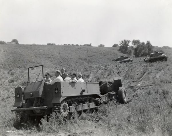 A M-5 high-speed prime mover carries men through a field. The original caption reads: "The M-5 high-speed prime mover, designed and engineered by International Harvester's Gas Power Engineering Department, at Chicago, for the Army, was put through a series of tests designed, according to a high Army official, 'to break the designer's heart'."