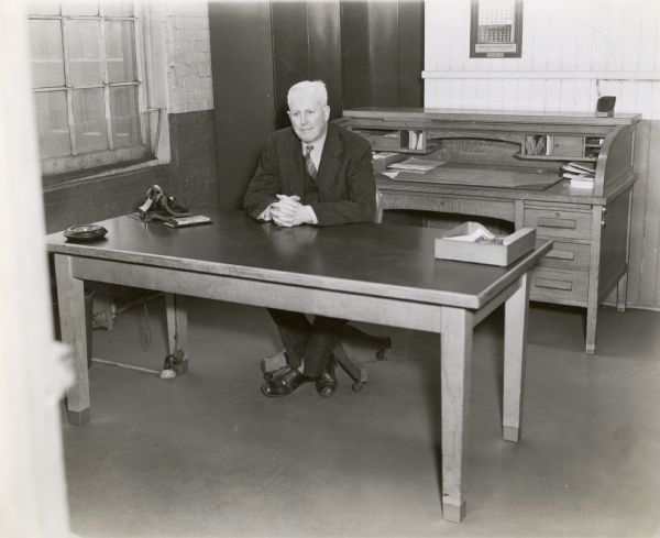 Paul Kane, chief engineer at International Harvester Company's farm machinery engineering department, sits behind a desk.