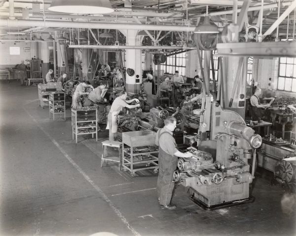 Elevated view of men working at machines in an International Harvester engineering shop. The original caption reads: "Scene from International Harvester Company's shop in the engineering department in Chicago, where the ideas of farm machinery designers are translated into metal and other materials."