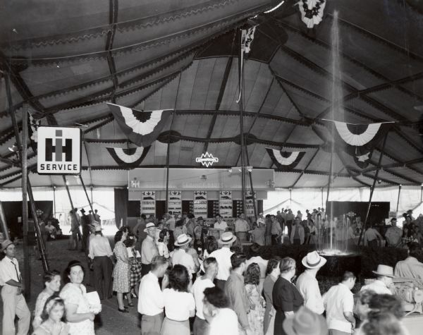 A crowd of people gathers in the International Harvester tent at the Illinois State Fair.