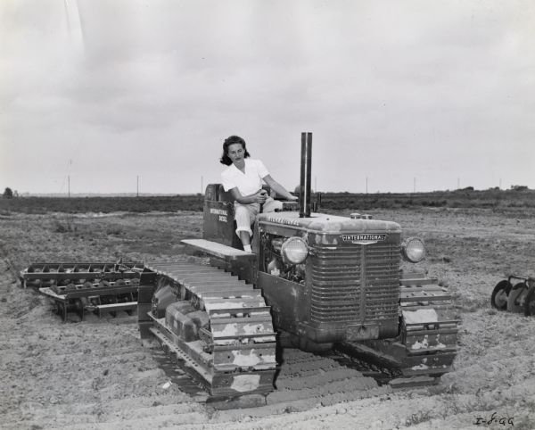Lucille Eltiste learns how to operate an International TD-9 crawler tractor with a Dyrr Offset Disk Harrow. The original caption reads: "With August Eltiste's son in the Coast Guard it was only natural for daughter, Lucille Eltiste to want to learn TracTracTor operation to fill his place on the Eltiste Ranch. Here she is learning how to operate a TD-9 with a Dyrr Offset Disk Harrow." Ms. Eltiste was likely taking part in International Harvester's "Tractorette" program.