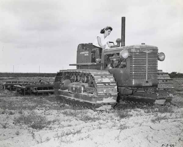 Esther Goubert of Santa Ana, California, takes the final field test of TracTracTor (crawler tractor) operation in the "Tractorette" program. The original caption reads: "Tractorette Esther Goubert of Santa Ana, California proves that she can take her Army brother's place on the Goubert Farm. Esther took her lessons seriously during Harvester Dealer August Eltiste's recent Tractorette Training Course and consequently will be a valuable aid to her father for the duration in growing Lima beans and Alfalfa on their 160 acre farm. She is shown here in her final field test at the controls of a TD-9 and Dyrr Offset Disk Harrow." International Harvester Company announced the "Tractorette" program in 1942. The plan was intended to address the farm labor shortage created by U.S. war mobilization. The plan called for local dealers to offer free training for thousands of farm women and girls in the operation of tractors and other farm machinery.