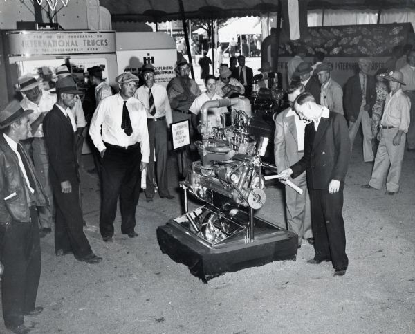 A crowd looks at a Blue Diamond engine on display at the Indiana State Fair. The text in the background reads: "A Few of the Thousands of International Trucks In The Indianapolis Area." The sign by the engine reads: "Used on Truck Models K-6, K-7."