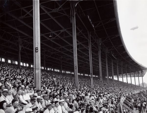 A large crowd sits in stadium-style bleachers to watch a horse race at the Iowa State Fair.