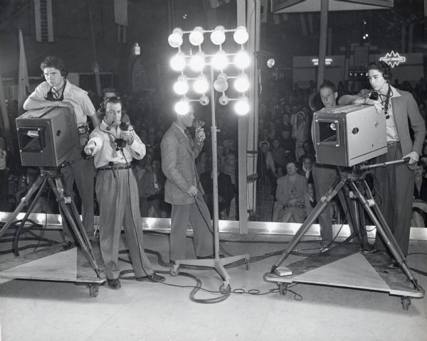 The television crew standing on stage in front of an audience at the Iowa State Fair.