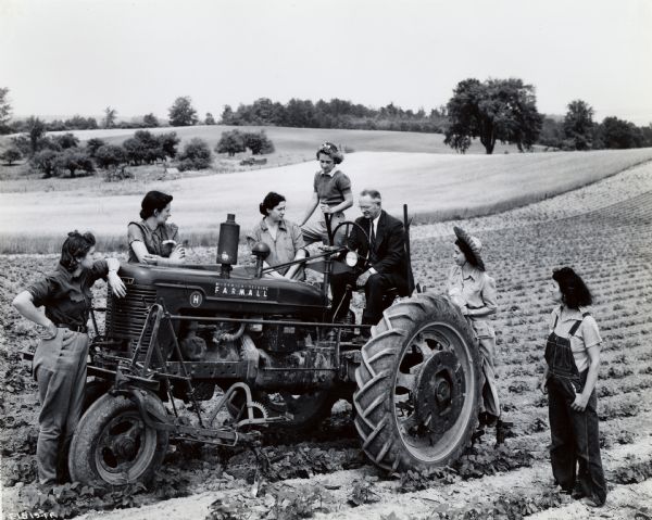 A group of participants in the "Tractorette" program gathers around a Farmall tractor operated by Fred R. Walkley, proprietor of Walkley Farm Equipment Company and program instructor.