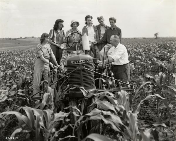 Several participants from a class of 22 "Tractorettes" standing around a Farmall tractor with their instructor, John Schneider, proprietor of the Nodaway County Implement Company.