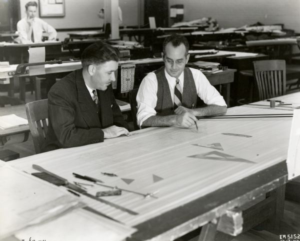A.H. Keller (left), chief engineer, sits next to C.M. Hyman, designer, at International Harvester Company's farm implement engineering department.