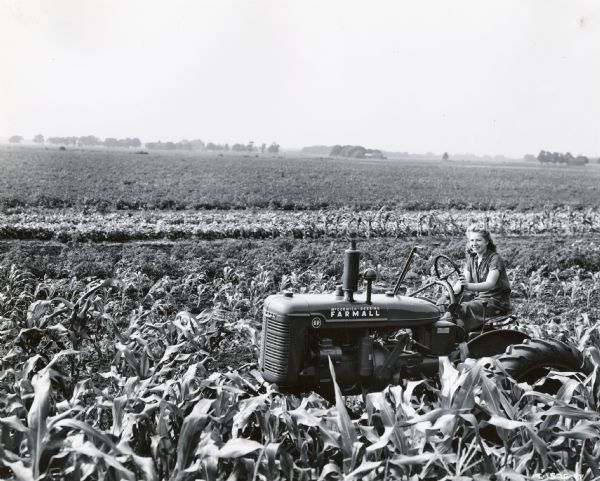 Elsie L. Meyer operating a Farmall AV tractor on her father's farm. The original caption reads: "Elsie L. Meyer of Hicksville, New York, not only operates Farmall-A on her father's small farm but does custom work. She is 17-years-old and has been driving tractors for three years."