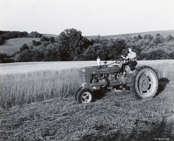 A Red Cross motor corps woman sitting on a Farmall H tractor at Herbert's Hill Angus farm. The original caption reads: "Red Cross motor corps women in Paoli and West Chester, Pennsylvania, took what might be called postgraduate tractorette courses. In the pictures several of the West Chester class are shown on the big, beautiful Herbert's Hill Angus farm where they did real farm tractor work on a variety of jobs." The woman in the photograph is possibly Mrs. P.F. Smith, Mrs. S.E. Smith, Mrs. Elizabeth M. Swayne, or Mary G. Baldwin.
