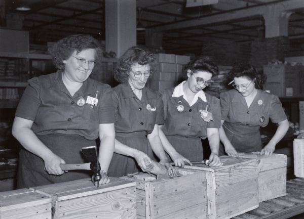 Four women are packing and closing wooden crates at International Harvester's Tractor Works.