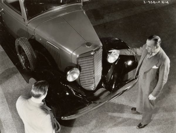 Elevated view of two men standing next to an International truck in what appears to be a dealership showroom.