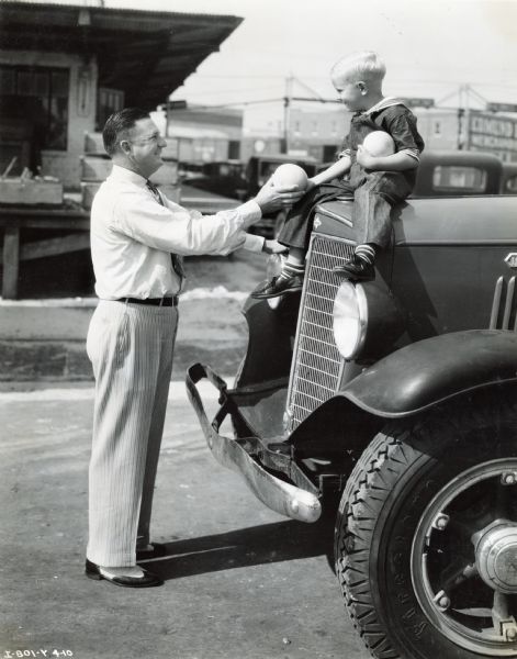 Neel S. Yent poses for a photograph with his son, Jackie, who is seated on the hood of an International truck. Neel was a truck salesman for the Orange State Motor Company, an International Harvester truck dealership.
