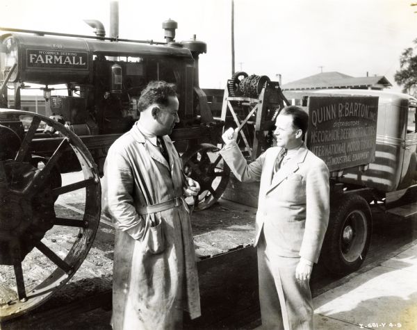 C.L. McCumber, service manager, and Quinn R. Barton, president of Quinn R. Barton, Inc., stand in front of a Farmall F-20 tractor loaded onto a truck. Quinn R. Barton, Inc. was an International Harvester dealership. The sign on the truck behind the men reads: "Quinn R. Barton, Inc.; Distributors; McCormick-Deering Tractors; International Motor Trucks; ... and Industrial Equipment."