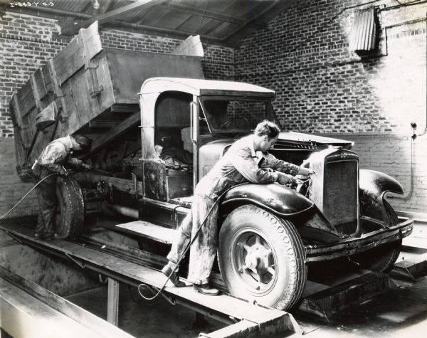 Mechanics H.C. Morris and H.F. Clantor grease an International Model A-5 truck at the City of Jacksonville Garage.