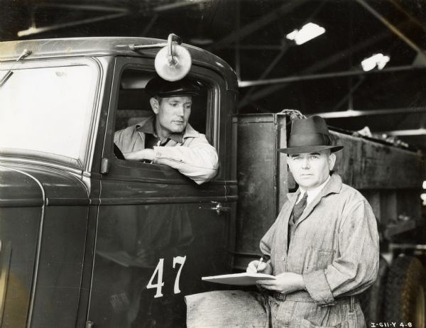 R.B. Jett, manager of the Atlanta City Garage, stands next to a truck marked "47". A man seated in the driver's seat looks out from the truck's window.