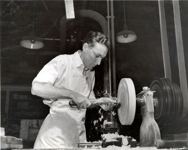A wood pattern-maker apprentice at McCormick Works (factory) turns a pattern on the faceplate of a lathe.