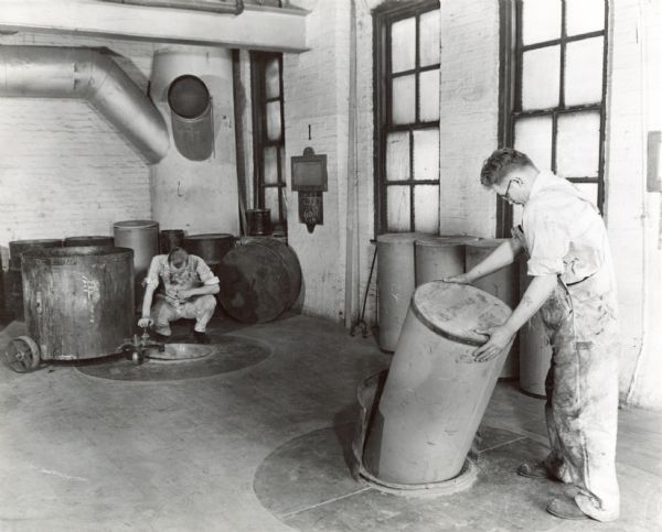 Factory workers in the Paint Department of McCormick Works charge vehicles and pigment into large ball units.