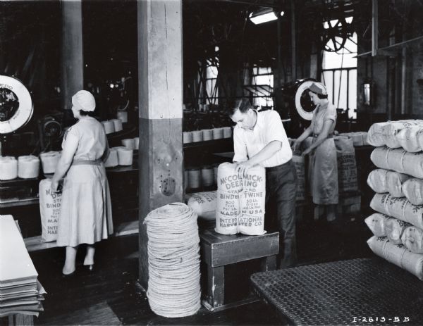 Female and male factory workers handle bags of twine in the McCormick Works Twine Mill.