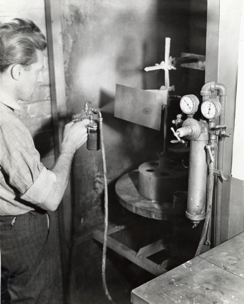 Factory worker in the McCormick Works Paint Department tests the spraying qualities of automotive enamels.