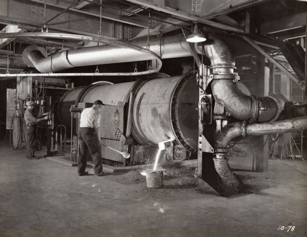 Factory workers take samples from the 8-ton Brackelsberg Furnace at McCormick Works. The original caption reads: "Furnace has three tap spouts. Large insulated pipe carries pre-heated secondary air; small pipe carries pulverized coal and primary air."
