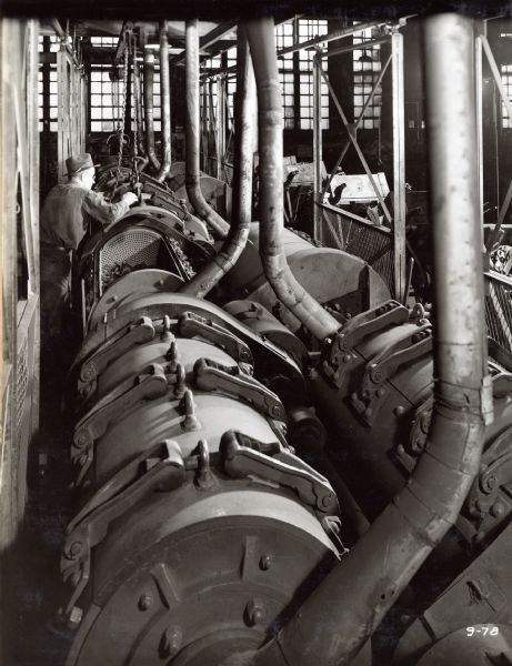 A factory worker stands next to the battery of roller bearing tumble mills at McCormick Works.