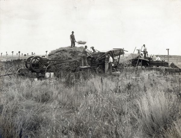 Men on an Australian farm use an International Harvester engine and hay press, and a Sterling thresher.