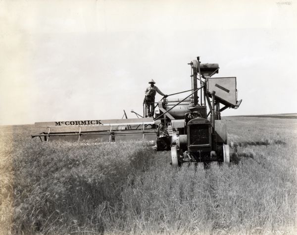 A man uses a McCormick 15-30 tractor and No. 11 harvester-thresher in an unspecified non-United States location. The original caption reads: "Note that the machines have been changed over from McCormick-Deering to McCormick for foreign use."