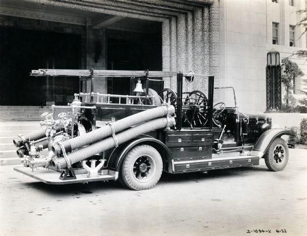 An International Harvester fire truck parked outside of a building with an ornately decorated entrance.
