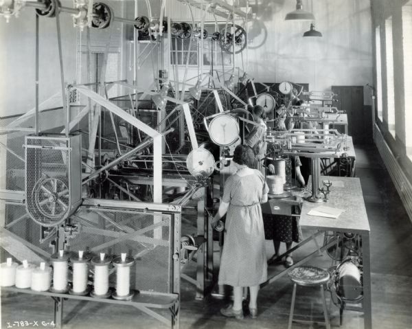Female factory workers balling twine in a room full of machinery at the McCormick Works Twine Mill.