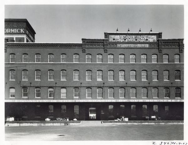 Exterior view of the McCormick Works factory building.  The signs on the building read: "McCormick Reaper Manufactory", "Established 1831", and "Quality is the Foundation of Our Business".