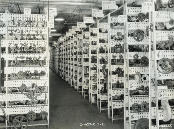 Storage room at the McCormick Works (factory) housing racks full of hanging gears and machinery parts.