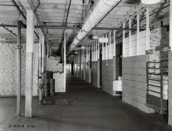Large storage area containing pieces of canvas for agricultural implements at the McCormick Works (factory). The bins in the right foreground are labeled: "B.C. 469, Platform Apron, 8 ft." and "JD. 603, Platform Apron, Canvas."