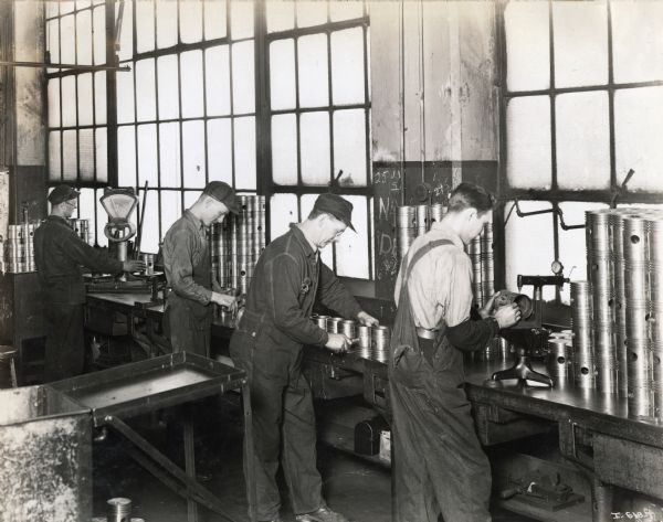Four factory workers standing along a countertop at the McCormick Works.