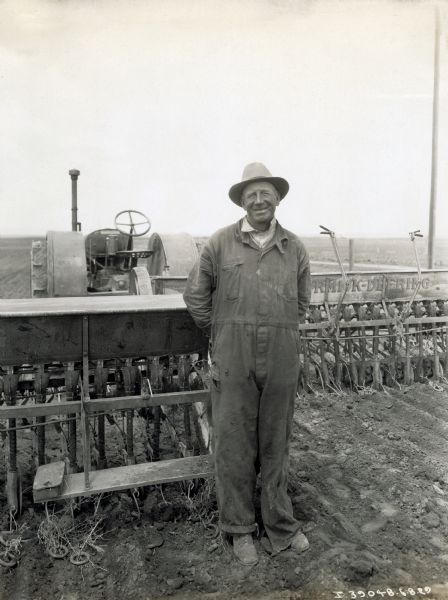 William Gustafson poses in front of a tractor and other McCormick-Deering farm equipment.