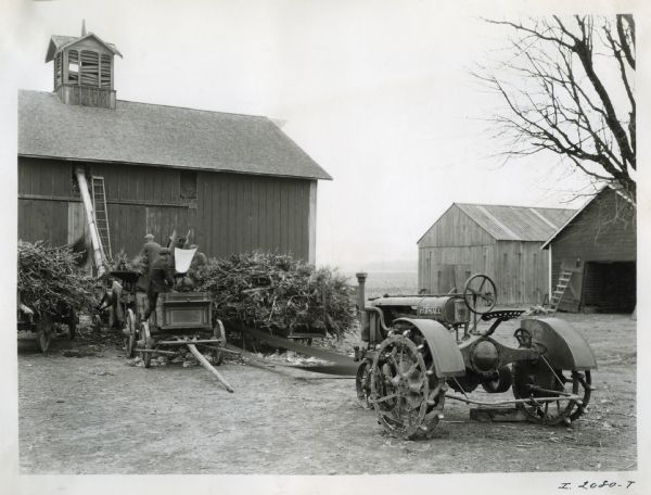 Men use a steel husker and shredder and a Farmall Regular tractor on the farm of J. Peter Peterson.