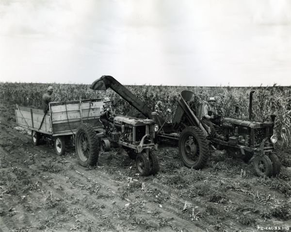 The Schuman brothers using Farmall tractors and an ensilage cutter in their farm field.