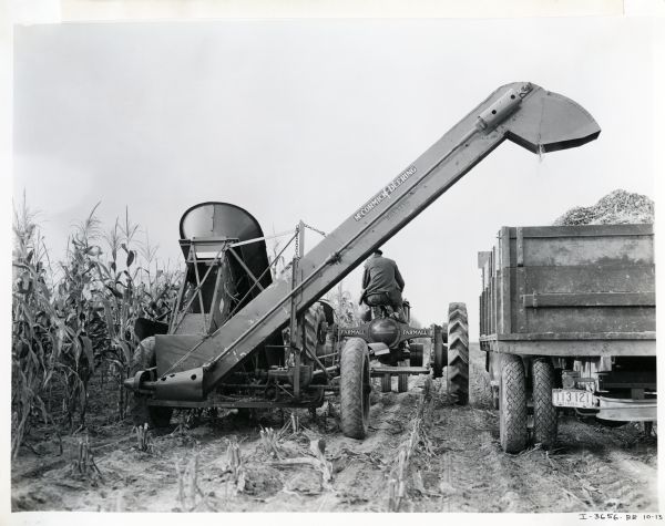A farmer using a Ronning ensilage cutter powered by a Farmall F-30 tractor to harvest corn on the Purdue University livestock farm.
