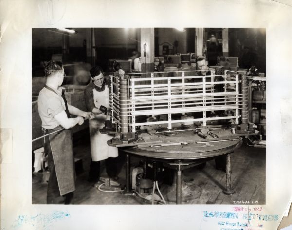 Men at West Pullman Works use tools to work on an electric-drive coil-winding machine.