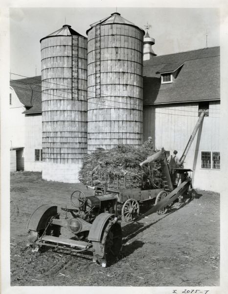 Men use a Farmall tractor and a steel husker-shredder(?) on the farm of Robert Rawley.