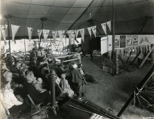A crowd sitting in the International Harvester tent at the Nebraska State Fair to watch a motion picture.