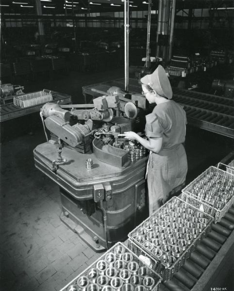 A female factory worker operates a machine in the ball bearing plant at West Pullman Works.