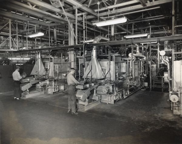 Factory workers standing at three heat-treating lines in the ball bearing plant at West Pullman Works.