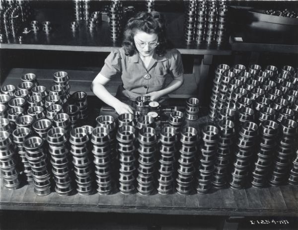 Overhead view of a female factory worker surrounded by stacks of metal parts at West Pullman Works.