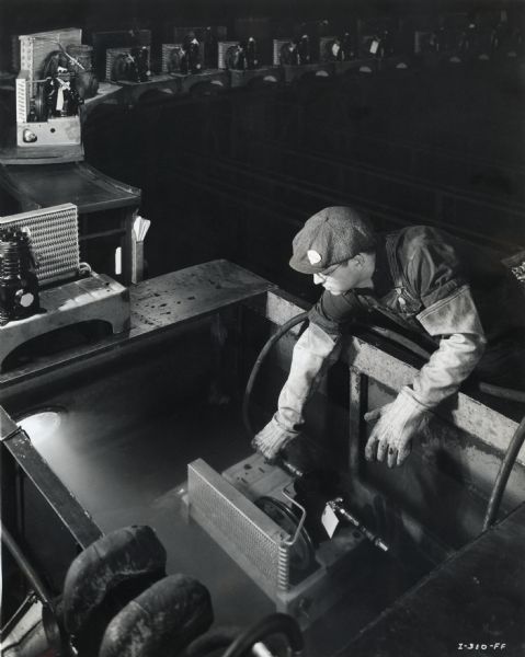 A factory worker at West Pullman Works wears long gloves while testing condensing units for leaks.